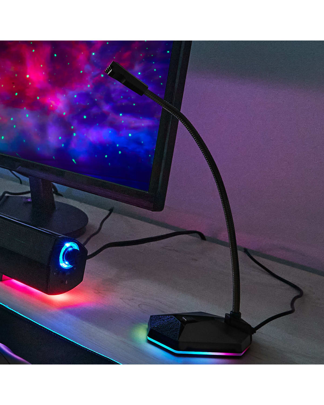 Photo showing gaming microphone with RGB on a table next to a monitor and led light box
