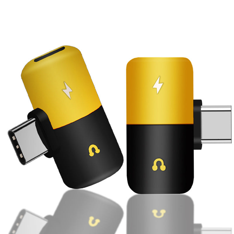 closeup view of type-c adapter with black and gold color design on it, engraved lightning and headphone icon on it